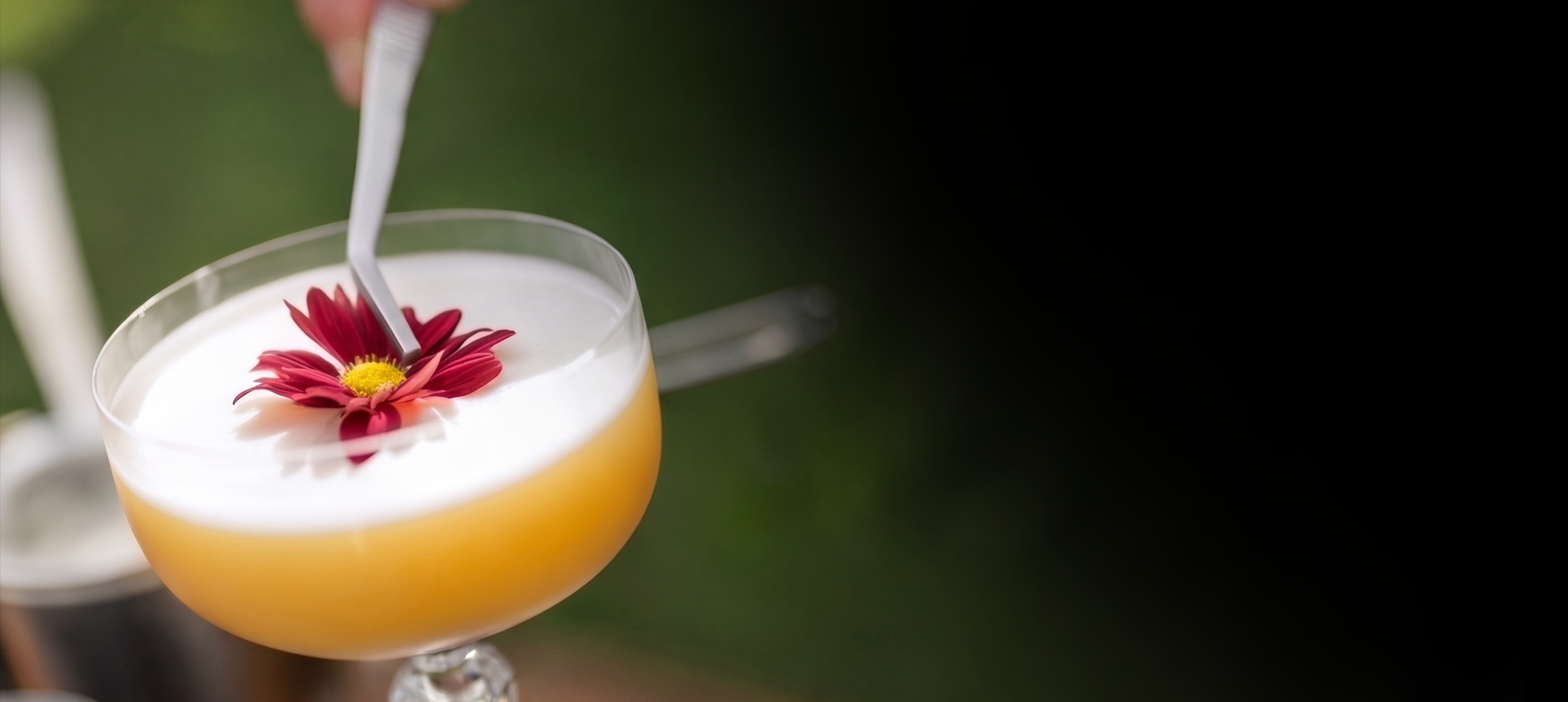 Drink autoral com flor vermelha sendo finalizado por um bartender da Strike